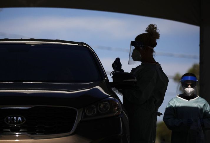 FILE - In this July 10, 2020, file photo healthcare workers test patients in their cars at a drive-thru coronavirus testing site in Las Vegas. (AP Photo/John Locher, File)