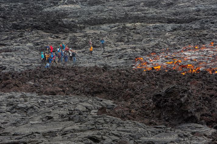 Ferðalangar úti á nýstorknuðu hrauninu. Undir niðri getur leynst rauðglóandi kvika.