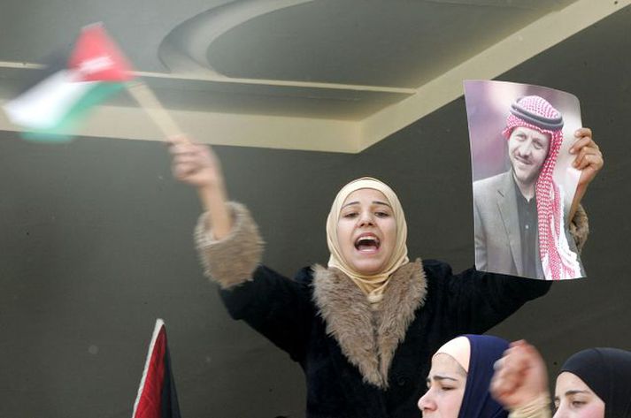 Jórdönsk kona veifar þjóðfánanum og mynd af Abdullah konungi í friðargöngu sem haldin var í Amman í gær. Vika er liðin frá tilræðunum mannskæðu.