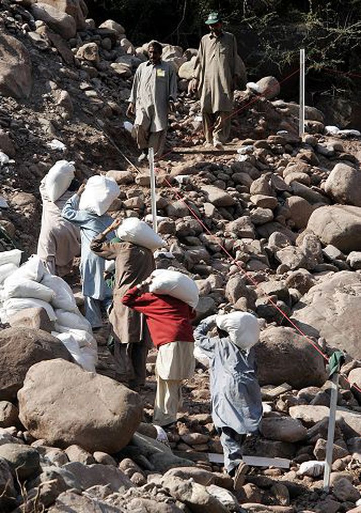 Hjálpargögn borin. Pakistanar bera hjálpargögn upp fjallsstíg á hamfara­svæðinu í Kasmír.