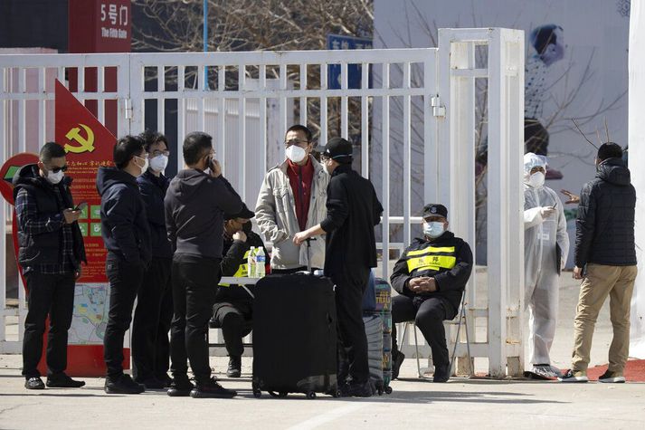 Öryggisverðir við inngang ráðstefnumiðstöðvar í Beijing sem kínversk stjórnvöld hafa breytt í sóttvarnamiðstöð þar sem fólk sem kemur til landsins er skimað fyrir veirunni.