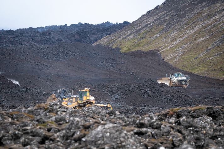 Menn freista þess að hamla framrennsli hraunsins með kælingu og stórum vinnuvélum.