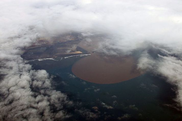 Eldgosið hófst um nóttina og nokkrum klukkutímum síðar ruddist flóð niður Markarfljót. Til vinstri á myndinni sést Landeyjahöfn sem virðist lítil í samanburði við aurbóluna sem myndast á haffletinum þegar milljónir rúmmetra af föstum gosefnum og aur æða í sjó fram. mynd/jarðvísindastofnun