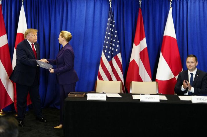 Mette Frederiksen (f.m.) tekur í spaðann á Donald Trump Bandaríkjaforseta við undirritun samningsins um Grænland í dag. Jens-Frederik Nielsen, forsætisráðherra Grænlands, klappar þeim lof í lófa.