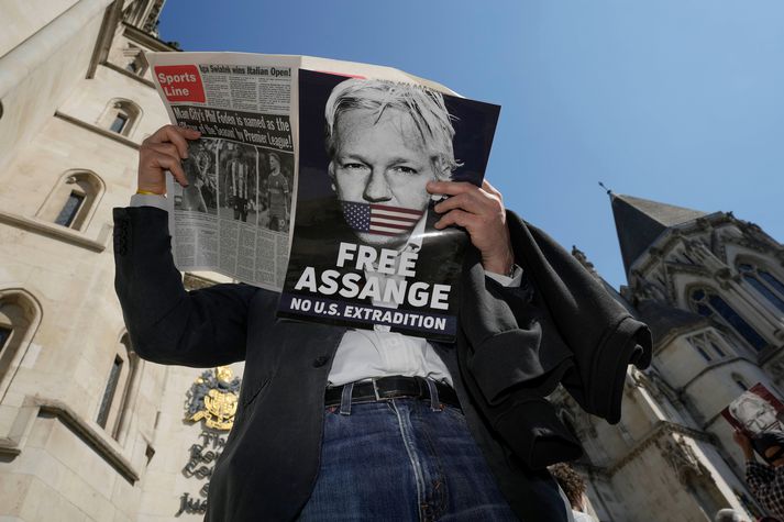 Mótmælandi les dagblað fyrir utan dómstólinn í London. Fjöldi stuðningsmanna mætti þangað til að styðja málstað Assange í dag.