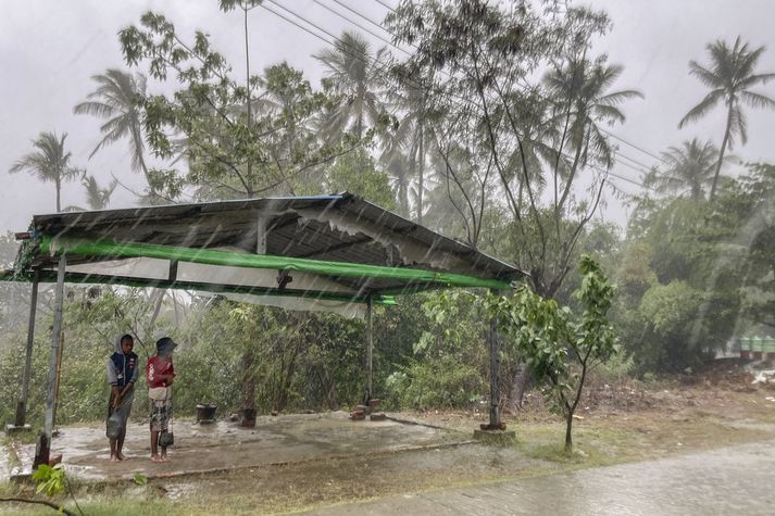 Börn leita skjóls fyrir rigningu á undan fellibylnum Mocha í Sittwe í Rakhine-ríki í Búrma í dag.