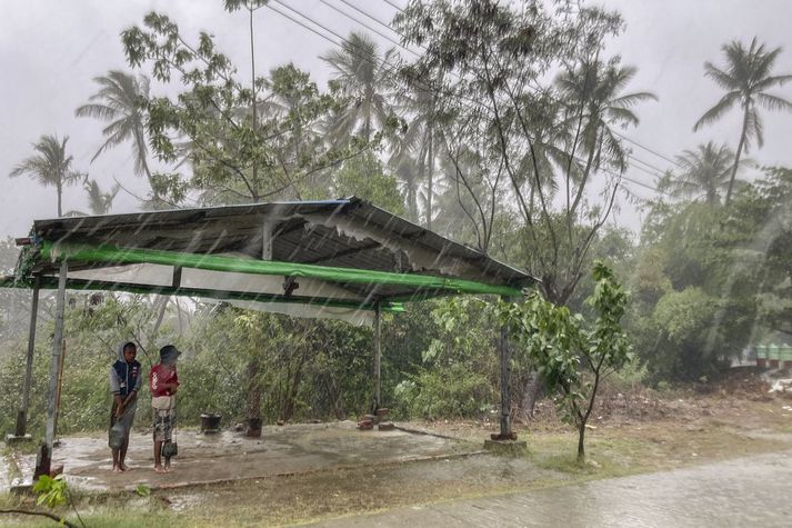 Börn leita skjóls fyrir rigningu á undan fellibylnum Mocha í Sittwe í Rakhine-ríki í Búrma í dag.