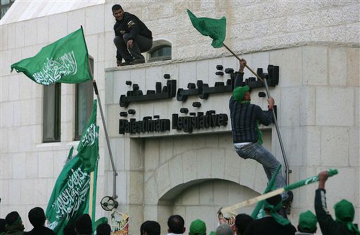 Hamas liðar klifra með fána sinn upp á þinghús heimastjórnar Palestínumanna.