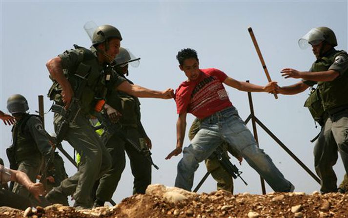 Ísraelskir hermenn umkringja palestínskan mótmælanda í Bilin í dag.