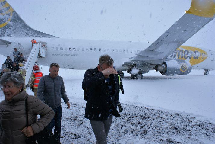 Andri ber hönd yfir höfuð sér en hér er verið að ferja hann ásamt öðrum farþegum úr flugvélinni yfir í rútu á Keflavíkurflugvelli í gær.