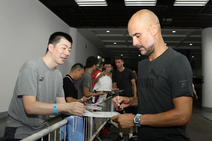 Pep Guardiola gefur hér eiginhandaráritun í Kína.