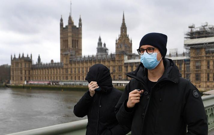 Grímuklætt fólk gengur fram hjá breska þinghúsinu í Westminster. Lítið verður um að vera þar næstu vikunnar.