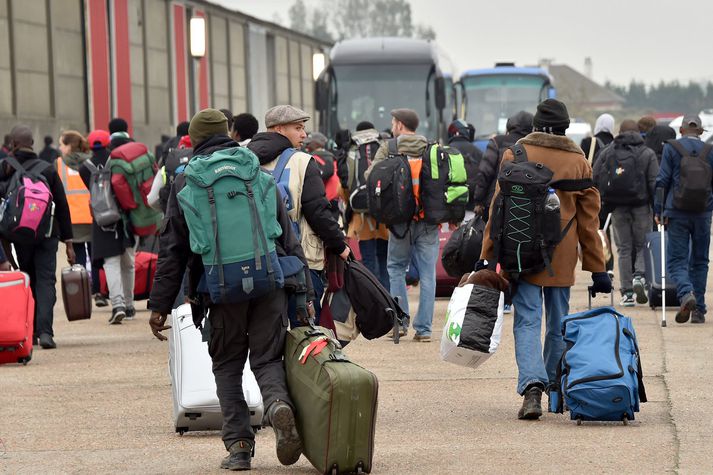 Flóttafólk í Calais á leið í rúturnar, sem flytja fólkið til .