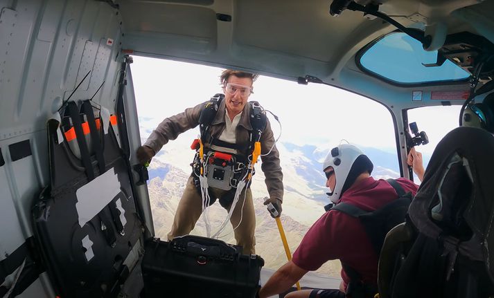Tom Cruise í þann mund að stökkva úr þyrlu.