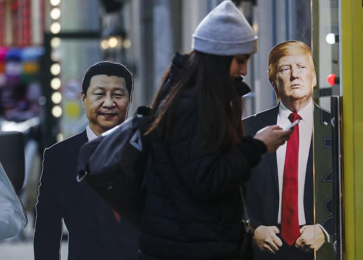 Kona stendur við útskornar myndir af Xi Jinping, forseta Kína, og Donald Trump Bandaríkjaforseta í Moskvu. Samskipti Kína og Bandaríkin hafa farið versnandi í tíð Trump sem hóf viðskiptastríð gegn stjórnvöldum í Beijing.