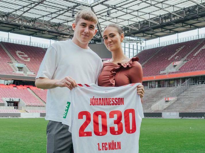 Ísak Bergmann Jóhannesson og kærasta hans Agnes Perla Sigurðardóttir með treyjuna sem sýnir að samningur Ísaks við Köln er til ársins 2030.
