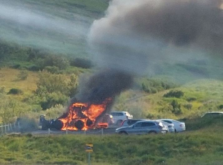 Eldurinn hefur borist úr gröfunni í nærliggjandi bíl.