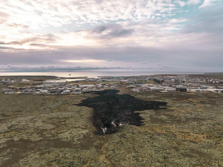 Grindavík úr norðri. Í forgrunni sést hraunið sem flæddi inn í bæinn og yfir nokkur hús í gær. Úti á sjó sést varðskip Landhelgisgæslunnar.