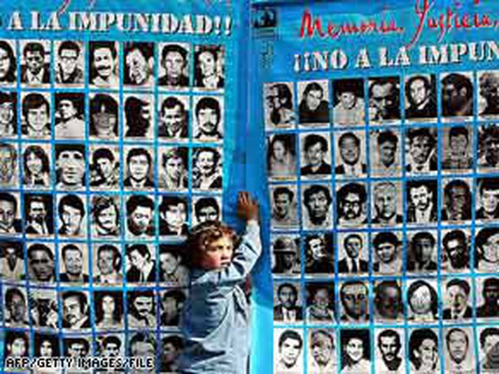 Barn stendur við vegg með myndum af fjölda Chile-búa sem enn er saknað síðan á Pinochet-tímanum. Myndin er frá árinu 2004.
