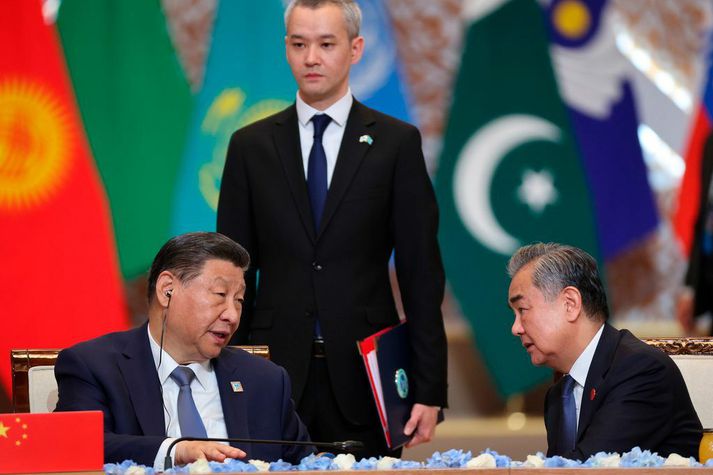 Xi Jinping Kínaforseti og utanríkisráðherrann Wang Yi ræða saman. Stjórnvöld í Kína hafa löngum freistað þess að taka sér hlutverk sáttasemjara í ýmsum deilum.