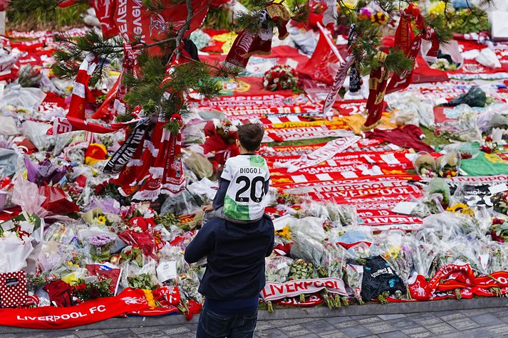 Blómahaf er fyrir utan Anfield til minningar um Diogo Jota. Hér er faðir með ungan son að skoða þessa sérstöku sjón.