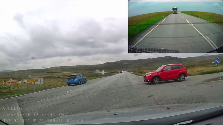 Rauði bíll ferðamannsins á leiðinni í veg fyrir bíl mæðgnanna. Í baksýnismyndavélinni sést flutningabíll á mikill ferð. Sem betur fer varð ekki árekstur.