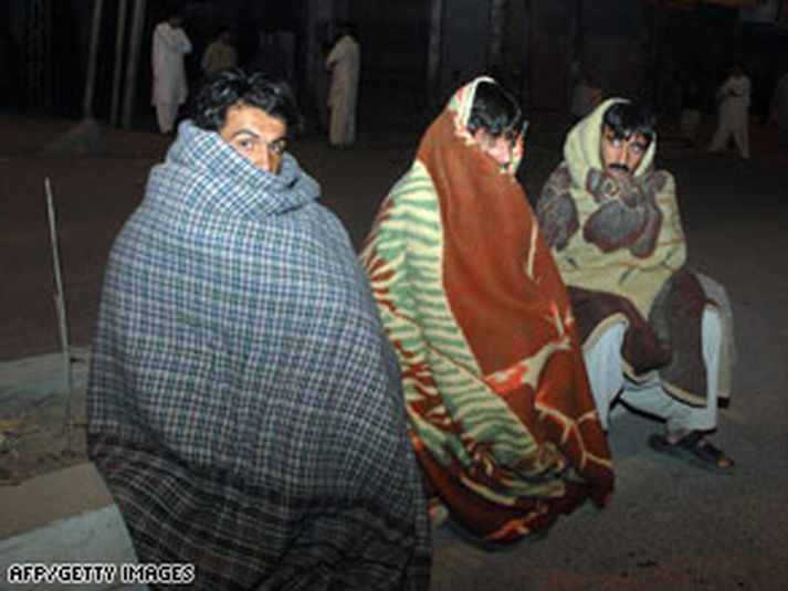 Fólk sem misst hefur heimili sín í skjálftanum situr á götum úti, sveipað teppum.