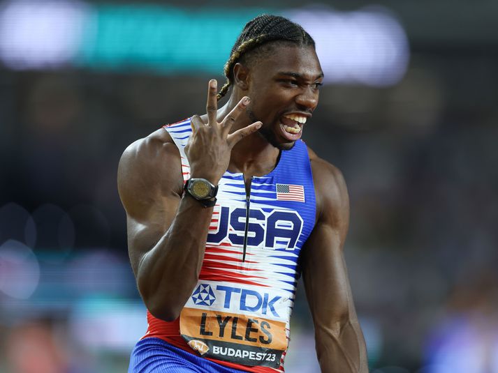 Noah Lyles gefur merki um gullin þrjú um leið og hann kemur í mark í boðhlaupinu.