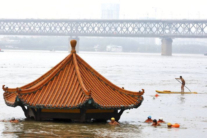 Maður á róðrarbretti rær fram hjá skála sem fór á kaf í flóði í Yangtze-fljóti í Wuhan í Kína í júlí. Vaxandi flóð eru á meðal afleiðinga loftslagsbreytinga af völdum manna.