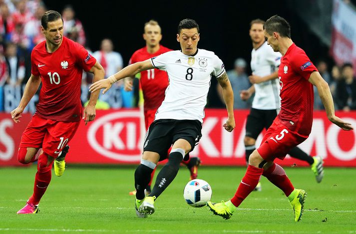 Mesut Özil í baráttunni við Grzegorz Krychowiak og Krzysztof Maczynski.