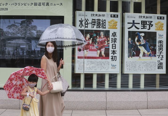 Tókýóbúar ganga fram hjá fréttum um japanska gullhafa á ólympíuleiknum.