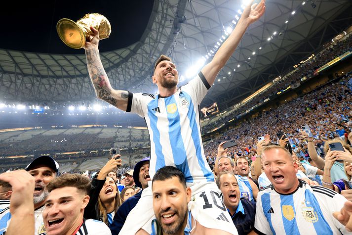 Lionel Messi borinn um völlinn með heimsbikarinn í hendi eftir sigur Argentínu í úrslitaleik HM í Katar 2022.