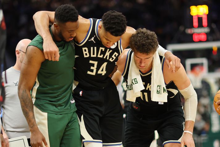 Thanasis Antetokounmpo og Brook Lopez hjálpa hér Giannis Antetokounmpo af velli í nótt.