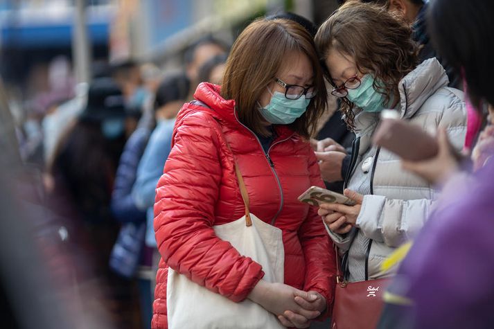 Myndin er tekin í Hong Kong þar sem fólk beið í röð eftir að fá fríar andlitsgrímur.