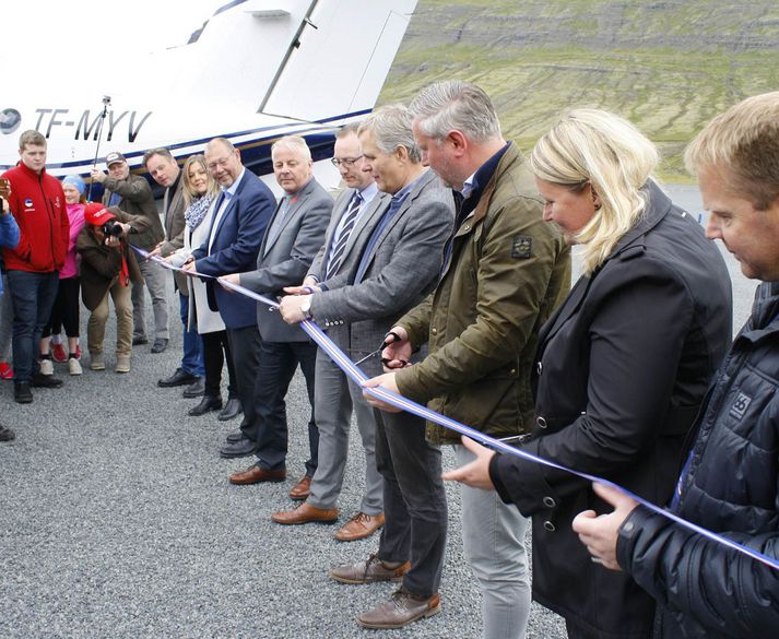 Samgöngumálaráðherra klippir á borðann og opnar Norðfjarðarflugvöll.