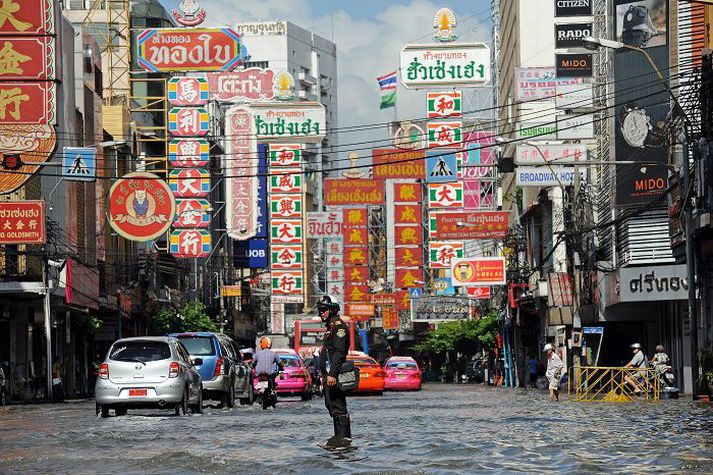 Umferðargata í Bangkok Lögreglumaður í Bangkok reynir að leiðbeina ökumönnum, sem aka um götur þaktar vatni.