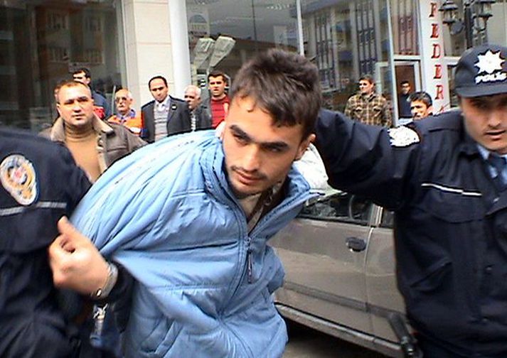 Handtaka Lögregla færir einn hinna grunuðu af vettvangi.