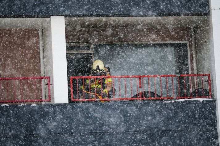 Slökkviliðsmaður á svölum íbúðarinnar við störf.