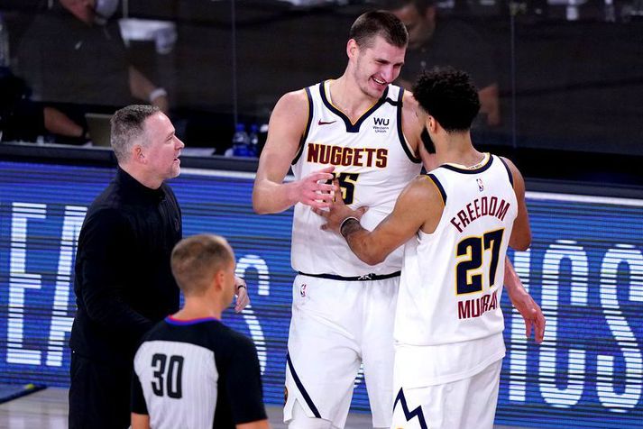 Michael Malone, þjálfari Denver Nuggets, fylgist með stjörnuleikmönnum sínum Nikola Jokic (15) og Jamal Murray (27) fagna sigri í nótt.