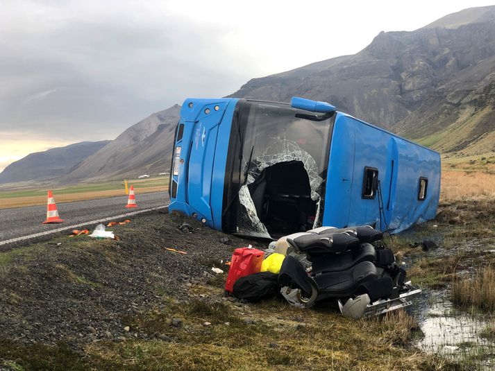 Rútan lenti á hliðinni utan vegar. Tveir um borð festust undir henni en voru losaðir með aðstoð heimamanna á næstu bæjum.