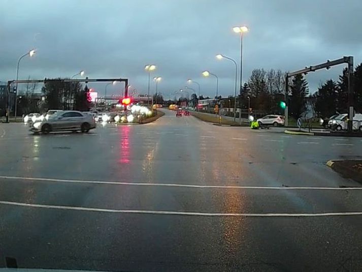 Grænklæddur hjólreiðamaður í götunni og gráum fólksbílnum ekið í burtu.