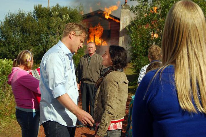 Bústaðurinn við Þingvallavatn í ljósum logum við tökur á Okkar eigin Osló. Þorsteinn Guðmundsson og Brynhildur Guðjónsdóttir haldast í hendur á meðan Laddi fylgist með í fjarska.