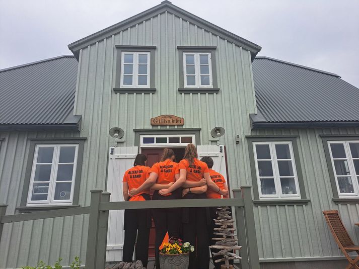 Alltaf sól á Sandi stendur á bolunum. Það verður þó ekki sól þar í það minnsta í tvær mínútur og sjö sekúndur á miðvikudaginn. 