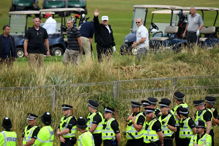 Fjölmennt lögreglulið stóð vaktina við Turnberry-golfvöll Trumps í dag. Forsetinn sést hér veifa mótmælendum, sem tóku illa í kveðjuna.