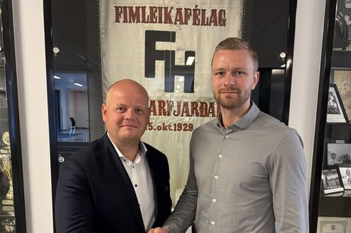 Ágúst Bjarni Garðarsson, formaður handknattleiksdeildar FH, innsiglar samninginn við Aron með handabandi.