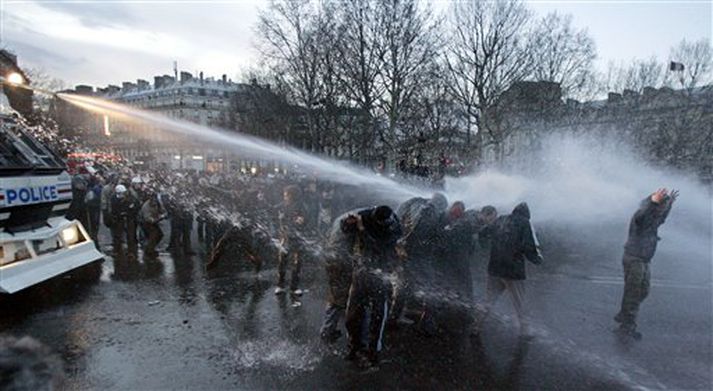 Lögregla sprautar á mótmælendur í París í gær.