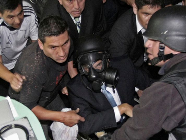 Rafael Correa, með gasgrímu, á leið út af sjúkrahúsinu umsetna.