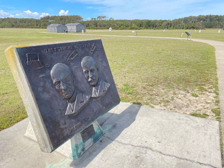 Bræðurnir Wilbur og Orville Wright flugu fyrstu flugvélinni á flötinni í Kitty Hawk, sem sést fyrir aftan. Þar er einnig búið að endurgera flugskýlið og skúrinn sem þeir bjuggu í þegar þeir gerðu flugtilraunir sínar á árunum 1900 til 1903.