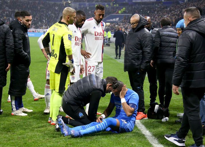 Dimitri Payet heldur um höfuðið á meðan að hlúð er að honum eftir flöskukastið.