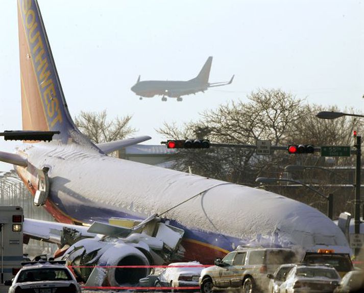 Rakst á bíla. Boeing 737-þota Southwest-flugfélagsins á slysstað í gær. Í bakgrunni sést önnur sams konar þota svífa inn til lendingar.